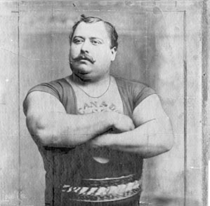 Louis Cyr, Canada, 1863-1912. Seine außerordentlichen Leistungen bestanden unter anderem darin, 500 lbs (227 kg) mit drei Fingern hochzuziehen und 4337 lbs (1967 kg) auf seinem Rücken zu tragen. Nach Ansicht von Ben Weider, dem ehemaligen Vorsitzenden der IFBB, ist Cyr der stärkste Mann, der je gelebt hat. (wikipedia)